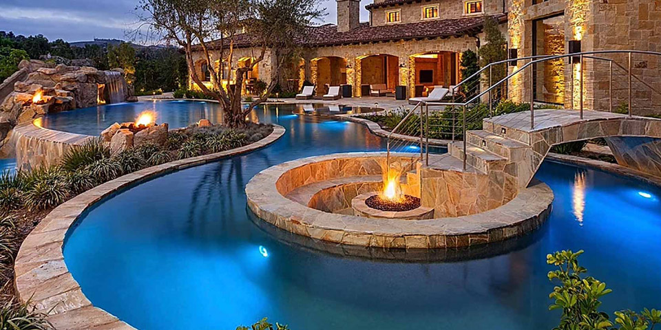Outdoor lighting around a pool with a fire pit in Carlsbad, CA.